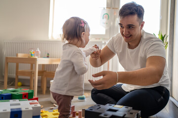 baby girl and her father young caucasian man with daughter playing at home happy sitting on the floor with toys in day fatherhood childhood family concept real people copy space - Powered by Adobe
