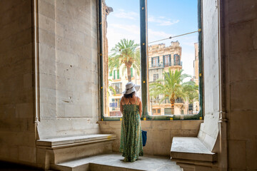 A woman looks out the large window of the medieval Guild hall or market hall La Llotja on the Mediterranean island of Mallorca, in the city of Palma de Mallorca, Spain.