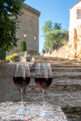 Glass of red dry wine and ruins of medieval castle of Châteauneuf-du-Pape ancient wine making village in France