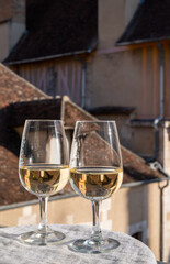 Tasting of white grand cru classe chablis wine with old French houses on background, Burgundy, France