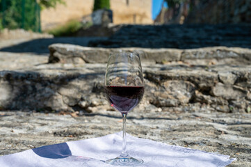 Glass of red dry wine and ruins of medieval castle of Châteauneuf-du-Pape ancient wine making village in France