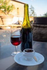 Tasting of red wine by old wine maker in Pierres Dorées region with yellow stone houses on south of Beaujolais region, France