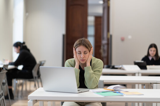 Stressed exhausted middle-aged woman mature student sitting in library holding head in hands, feeling unmotivated to study for exams, having learning difficulties while getting second higher education