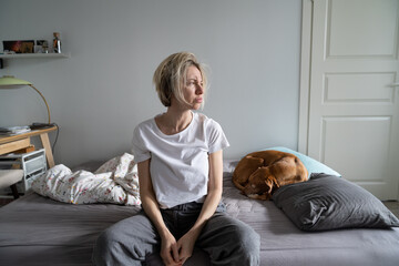 Mental disorders in mid-life. Unhappy depressed middle-aged woman living alone with dog sit on bed...