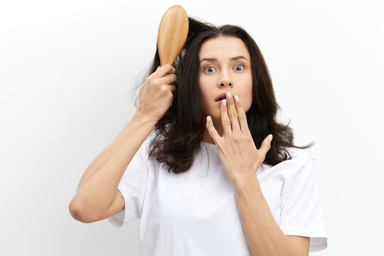 a close, horizontal photo of a frightened, emotional woman covering her mouth with her hand with a comb stuck in her hair