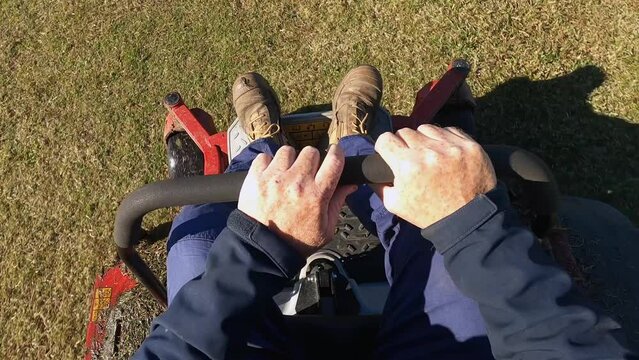 A man holds on tightly, driving a lawn tractor mower over grass. Point of view.