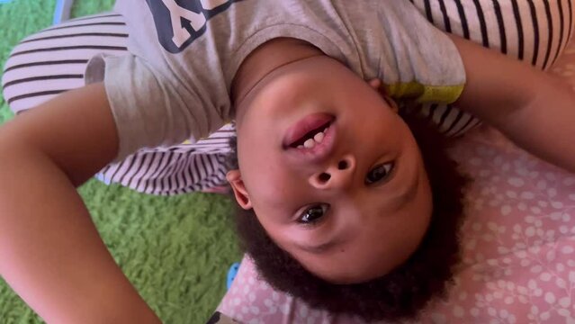 Exotic, adorable and lovely two year old afro european child playing upside down over mum legs with dady.