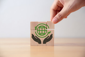 Hand of young man put wooden cube with green world icon on table,  Save world,  sustainable...