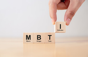 Psychological and personality test concept, Hand puts wooden cubes with MBTI, Myers-Briggs Type Indicator on table. - obrazy, fototapety, plakaty