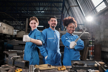 Multiracial industry workers in safety uniforms collaborate with unity, act with tools, and express happy work together with smile and cheerful in mechanical factory, professional engineer occupation.