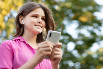 Overjoyed pretty girl wears in pink get carry away with music. Asian teenager girl use smartphone and enjoy favorite playlist via stereo headphones, relaxed sings along with carefree expression. High