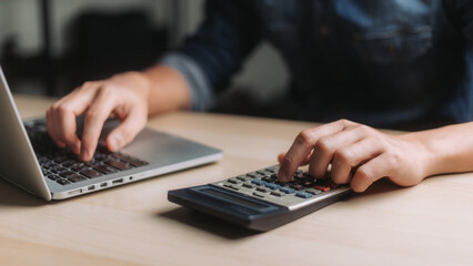 Man accountant using calculator and laptop computer in office, businessman working at home, finance and accounting concept.