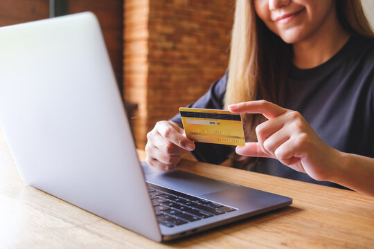 Closeup image of a woman holding credit cards while using laptop computer for online payment