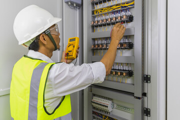 Electrician installing electric cable wires and fuse switch box. Multimeter in hands of...