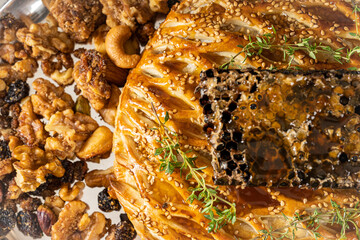 Close up of puff pastry bread with honey in honeycomb plated with walnuts, raisins, and rosemary