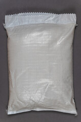 A full white bag against a gray background. Closed bag with food or other products. Top view. Copy space for text and design elements.