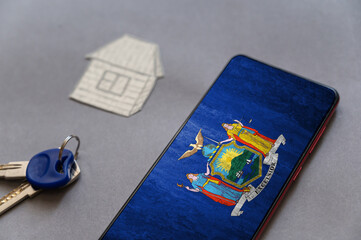 Smartphone, door keys, and paper house on gray background. New York State flag on screen of your device. Buying or renting homes. Moving to live in New York State. Selective Focus.