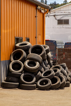 Stacked tires await disposal outside of a tire repair shop.
