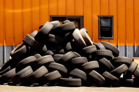Stacked tires await disposal outside of a tire repair shop.