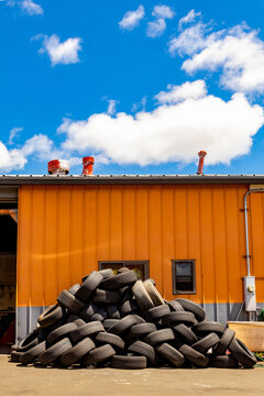 Stacked tires await disposal outside of a tire repair shop.