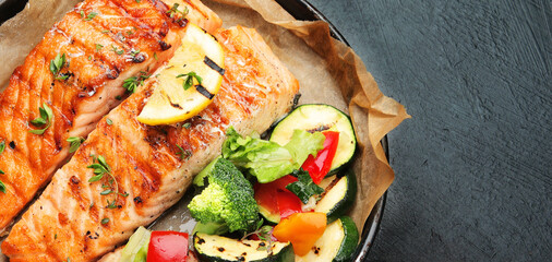 Salmon steak with vegetables on dark background.