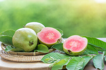 Sweet Red Guava fruit with leaf on blur garden background, Fresh Pink Guava fruit on wooden basket over natural farm background.
