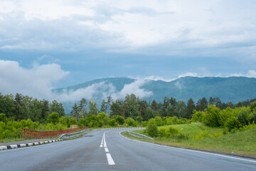Empty road. Speedway without cars in mountains amid pine forests. Adventure or road trip background.