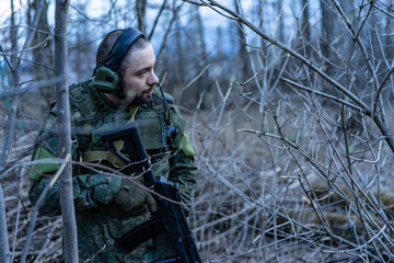Obraz premium soldier in the forest. a man in military uniform in the branches of trees, in an ambush with a weapon, rifle or machine gun. military actions. airball game