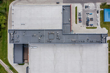 aerial view of warehouse shingle roof and parking lot with parked cars