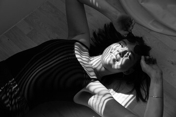 girl in black, in sunglasses in the studio. laughing, sitting or lying on the floor in the sun....
