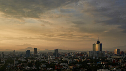 Fototapeta premium panoramic photo of a beautiful sunrise in mexico city with volcanos in the background (Iztaccíhuatl, popocatepetl).
