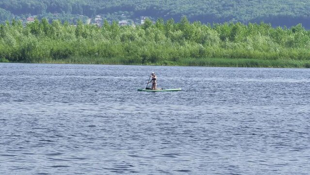 A girl rides on an inflatable board on a river on a summer day . Sports and recreation. Lifestyle.