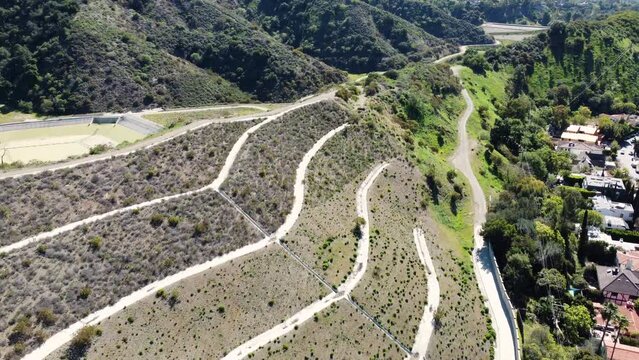 Aerial drone forward moving shot of winding road and posh mansions along the hillside in Beverly Hills, California, USAon a bright sunny day. 4K.