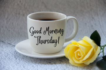 Good morning Thursday text on coffee cup yellow flower on blurred marble background.