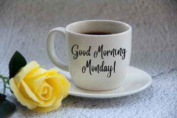 Good morning Monday text on coffee cup yellow flower on blurred marble background.