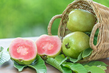 Fresh Pink Guava fruit on blue  wooden basket over green bokeh background. Sweet Red Guava fruit with leaf on blur garden background.