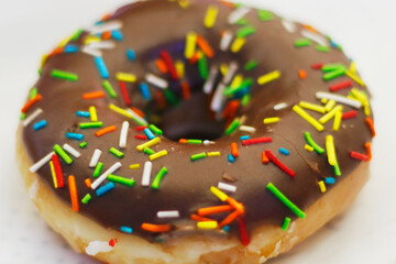 chocolate coated doughnut or donut with sprinkles on in close up