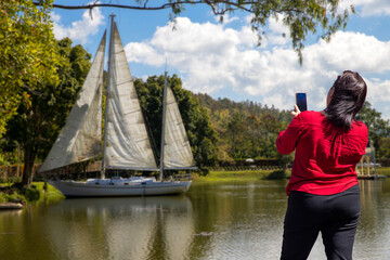 Fototapeta premium woman takes a photo of sailboats anchored in the bay. with mobile phone