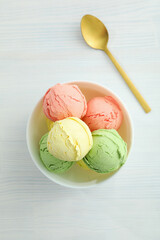 Bowl with ice cream scoops on white wooden table