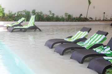 Abandoned sun-beds in swimming pool with towels on them
