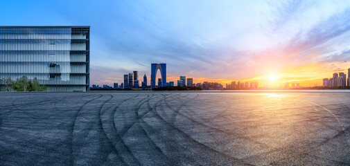 Asphalt road ground and city skyline with modern commercial building at sunset in Suzhou, China.