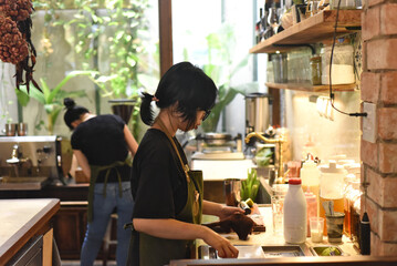 Vietnamese waitress getting ready an order in a coffee shop  