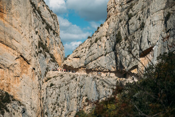 Fototapeta na wymiar Spectacular cliff with a walkway inside the rock with people doing hiking trips. Congost de Mont Rebei, Catalonia, Spain.