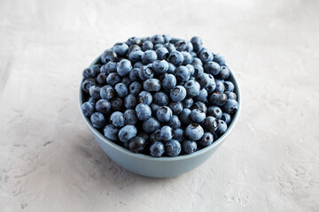 Raw Organic Blueberries in a Bowl on a gray background, side view.