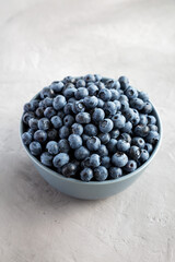 Raw Organic Blueberries in a Bowl on a gray surface, side view.