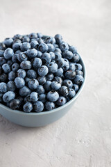 Raw Organic Blueberries in a Bowl on a gray background, side view.