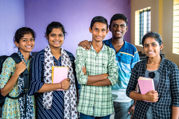 group of college students confidently standing with books and backpack at classroom by looking at...