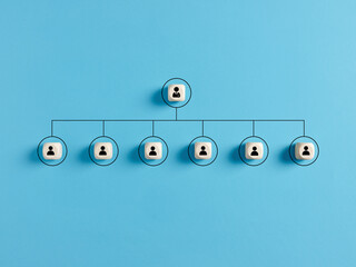 Company hierarchical organizational chart of wooden cubes on blue background.