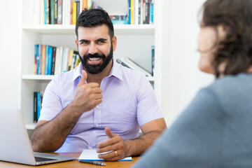 Happy businessman showing thumb up to client