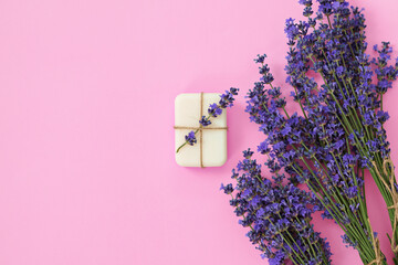 Top view of lavender soap and flowers on pink background